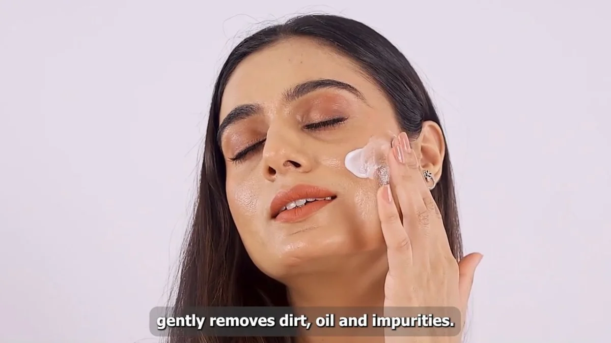 A creator applies a white skincare product to her cheek in a close-up filmed demonstration