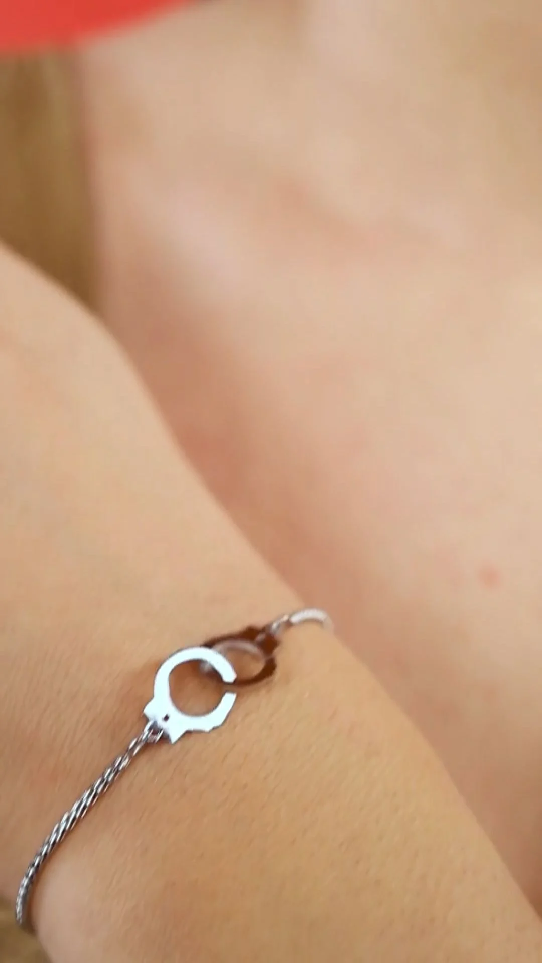 Close-up of a woman's wrist wearing a fine silver bracelet with a cuff charm against a warm skin-tone background, a jewellery creator detail shot that needs clear edit rights in the UGC usage rights India contract