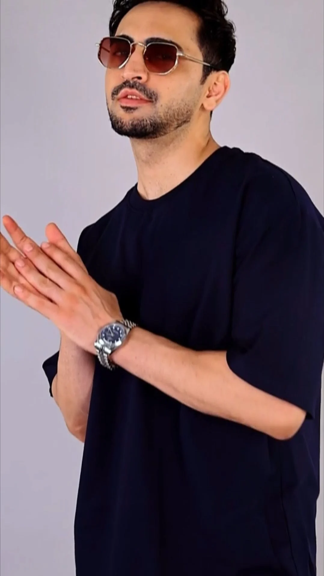 Indian male model in a navy oversized t-shirt and a wristwatch posing three-quarter on a white studio background as part of an apparel shot list for Amazon clothing images