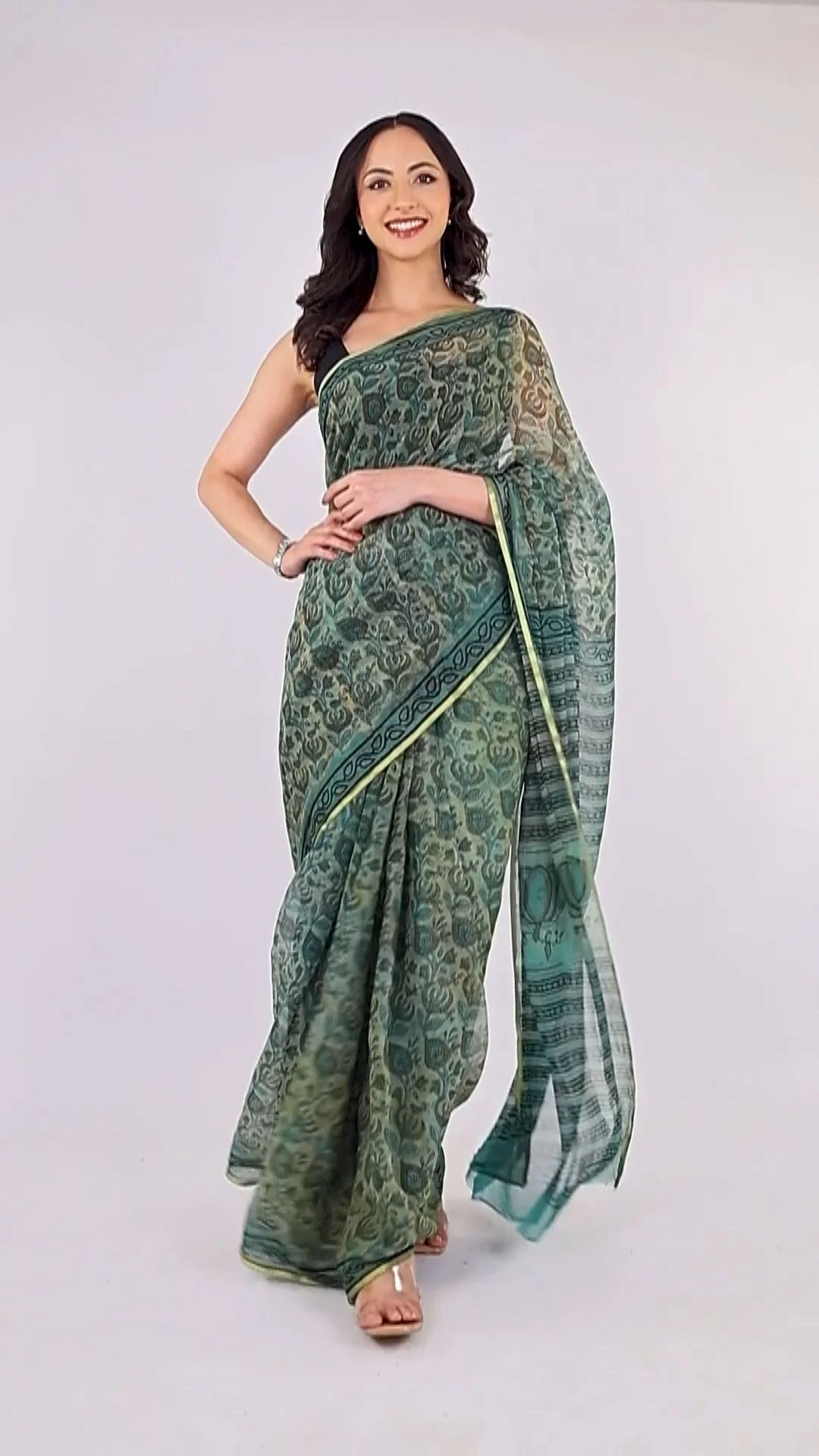 Full-length studio photograph of a woman wearing a green patterned sari with the drape, hem and garment silhouette visible